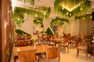碧瑶Aura One Hotel的餐厅设有木桌和椅子,种有植物