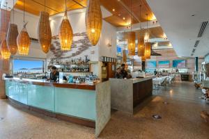 埃克斯茅斯曼塔雷宁格罗海滩度假酒店的一家餐厅,那里有酒吧,有人坐在里面