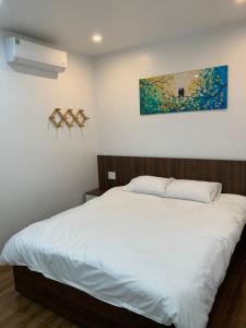 Kiến AnAdal Motel的卧室配有一张白色床,墙上挂有绘画作品