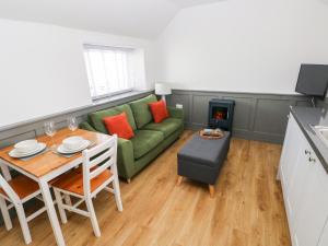 桑德斯富特Star Cottage的客厅配有绿色沙发和桌子