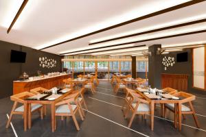 提喀迪Keys Prima By Lemon Tree Hotels, Thekkady的餐厅设有木桌、椅子和窗户。