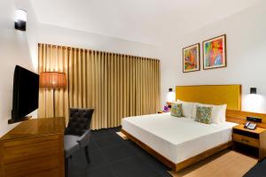 提喀迪Keys Prima By Lemon Tree Hotels, Thekkady的一间卧室配有一张床、一张书桌和一台电视