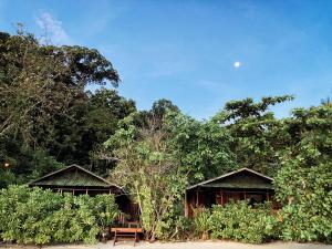 TapokrengRaja Ampat Eco Lodge的两座小屋,在一些树前设有长凳
