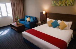 马斯喀特Best Western Premier Muscat的酒店客房带大床和蓝椅