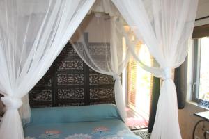 Le Bois de NèflesLodge Ylang Ylang, LIANE DE JADE 974 -piscine - jacuzzi privatif的一间卧室配有一张带天蓬和窗户的床