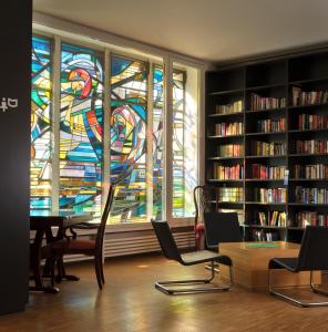 Remerschen申根青年旅舍的一个带彩色玻璃窗和桌椅的图书馆