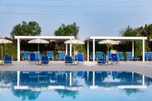 米内尔维诺迪莱切Dolmen Sport Resort的一组椅子和遮阳伞,位于游泳池旁