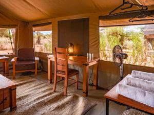 安博塞利Tulia Amboseli Safari Camp的帐篷内的房间,配有桌椅