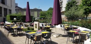 巴黎B&B HOTEL Paris 17 Batignolles的一组桌子和椅子,配有紫色雨伞