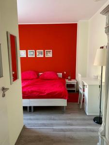 莱比锡die Senfbude - schöne, ebenerdige 2-Raum-Apartments mit Stellplatz und Terrasse的红色的卧室,配有一张红色墙壁的床