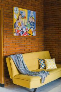 伦邦Amarillo Lembang的砖墙上一张黄色的长沙发,上面有毯子