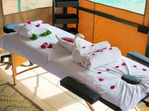 安博塞利Tulia Amboseli Safari Camp的一张带毛巾和鲜花的医院床