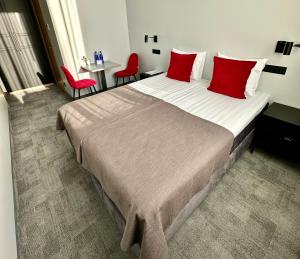 TõrvaTõrva Veemõnula Spaahotell的一间卧室配有一张带红色枕头的大床