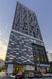 吉隆坡Chambers Kuala Lumpur by Five Senses的一座高大的建筑,前面有汽车停放