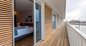 不来梅港THE LIBERTY Hotel Bremerhaven BW Signature Collection的木制阳台的卧室配有一张床