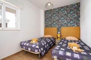 阿尔布费拉Apartamentos Old Town by Umbral的一间卧室设有两张床,墙上贴有壁纸。