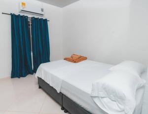 圣何塞德尔瓜维亚雷Casa Guaviare, La Mejor Opción Para Ti的客房内的白色床和蓝色窗帘