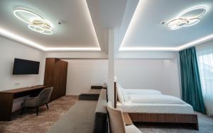 ScheiaHotel Ariata的酒店客房设有一张床、一张书桌和一台电视机。