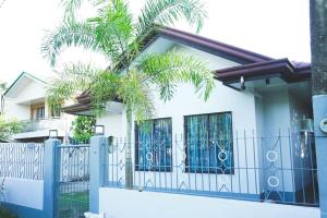 LagunaCosiHome Guesthouse的一座拥有蓝色围栏和棕榈树的房子