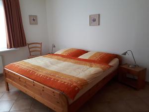 费马恩Ferienhaus Hopp的一间卧室配有一张带橙色毯子和灯的床