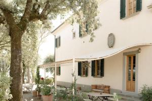 基安蒂格雷夫Villa de' Ricci Rignana di Sveva Rocco di Torrepadula的白色的房子,有桌子和树