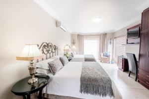 波切夫斯特鲁姆Adato Guesthouse的白色卧室设有两张床和一张桌子