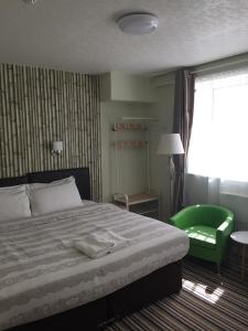 伯恩茅斯特里戈霍姆酒店的一间卧室配有一张床和一把绿色椅子