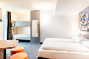埃姆登B&B Hotel Emden的酒店客房带两张床和一张桌子以及椅子。