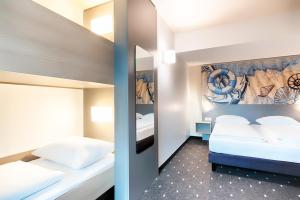 埃姆登B&B Hotel Emden的一间卧室设有两张床,墙上挂着一幅画