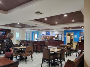 圣安东尼奥Holiday Inn Express & Suites San Antonio West Sea World Area, an IHG Hotel的站在带桌椅的餐厅里的人