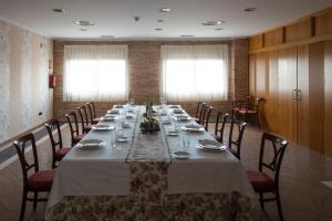 普拉森西亚Hospedium Hotel Doña Mafalda de Castilla的长长的用餐室配有长桌子和椅子