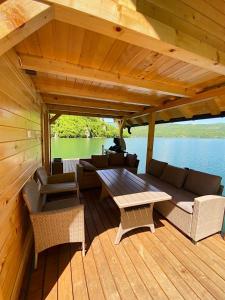 佩鲁恰茨Floating House Perućac的船上的木甲板上配有沙发和桌子