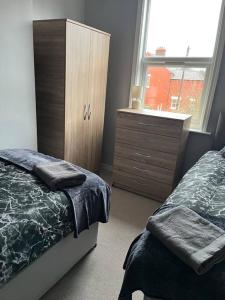 利物浦2 bed house near Sefton Park & Lark Lane的一间卧室配有一张床、一个梳妆台和一扇窗户。