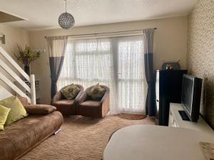 大雅茅斯Cosy and Comfortable Holiday Chalet 10 minutes walk to the beach, Norfolk的带沙发和电视的客厅