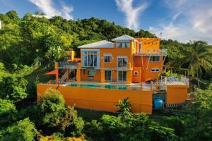 别克斯Vieques Villa Gallega - Oceanview w/Infinity Pool的一座橘色的房子,在树上设有一个游泳池