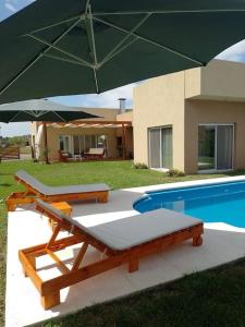 Villa Rosacasa con pileta climatizada, tiempo para descansar, Pilar的一个带两张床和大遮阳伞的游泳池