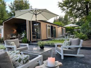 贝克贝亨Luxe vakantiehuis “Saalien”的庭院配有椅子和桌子及遮阳伞
