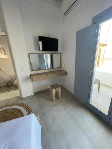 斯希努萨岛Sohoros Luxury Suites的白色的客房设有电视、桌子和窗户。