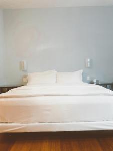 圣克鲁兹太平洋之蓝旅馆的一张白色大床,配有白色床单和枕头