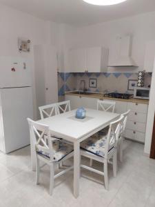 阿尔盖罗Casa Alghero Lido的厨房配有白色的桌椅和冰箱。