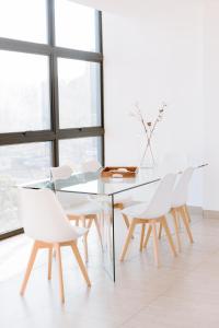 圣萨尔瓦多O & D’s Gallery Apartment的一间设有玻璃桌和白色椅子的用餐室