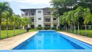 托拉Condo Golf B3 F3 Hacienda Iguana的棕榈树屋前的游泳池