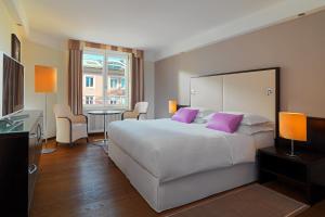 萨尔茨堡萨尔茨堡喜来登大酒店的卧室配有一张带紫色枕头的大型白色床。