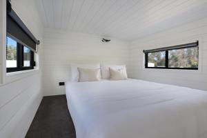 伊登Boydtown Beach Holiday Park的白色的窗户客房内的一张白色的床