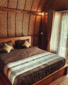 BesakihBesakih Homestay & Villa的木制客房的一张床位,设有窗户