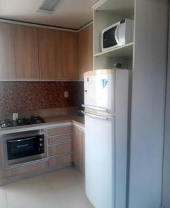 阿雷格里港Apartamento 5 min do Consulado Americano Porto Alegre的厨房配有白色冰箱和微波炉