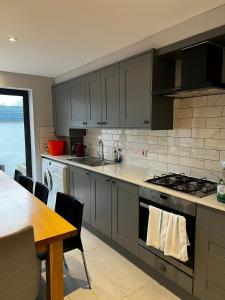 Hackbridge2b Seymour road的厨房配有灰色的橱柜、桌子和桌子以及用餐室。