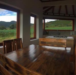 阿基塔尼亚Villa Rosario的一间带木桌和2扇窗户的用餐室