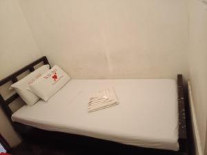 曼达维市WJV INN Mandaue Centro的一张带白色床单的小床和一本书