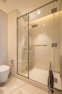 迪拜Luxurious Beachfront Apartment的一间带卫生间的浴室内的玻璃淋浴间